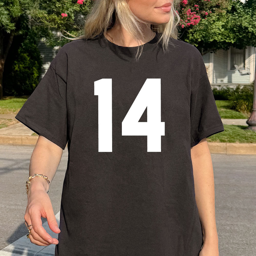 Person wearing a black t-shirt with the number 14 on it, standing outdoors.