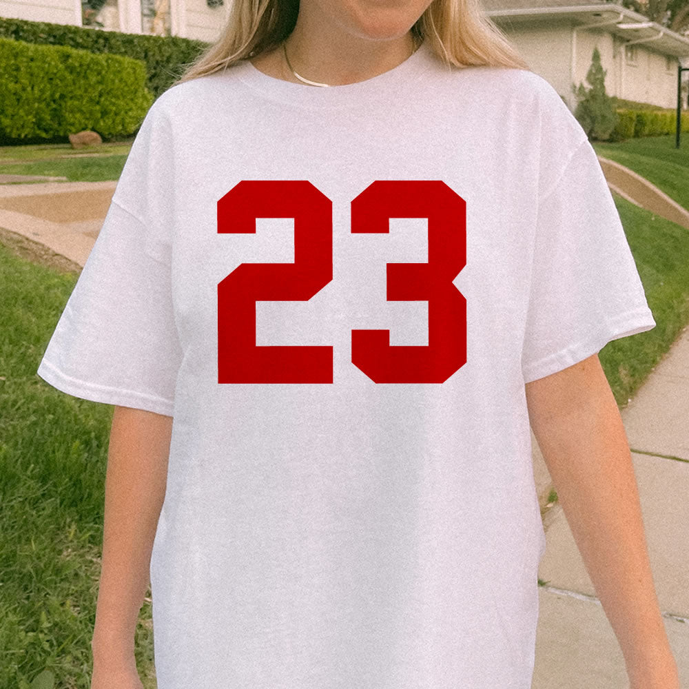 Person wearing a white t-shirt with red number 23 outdoors