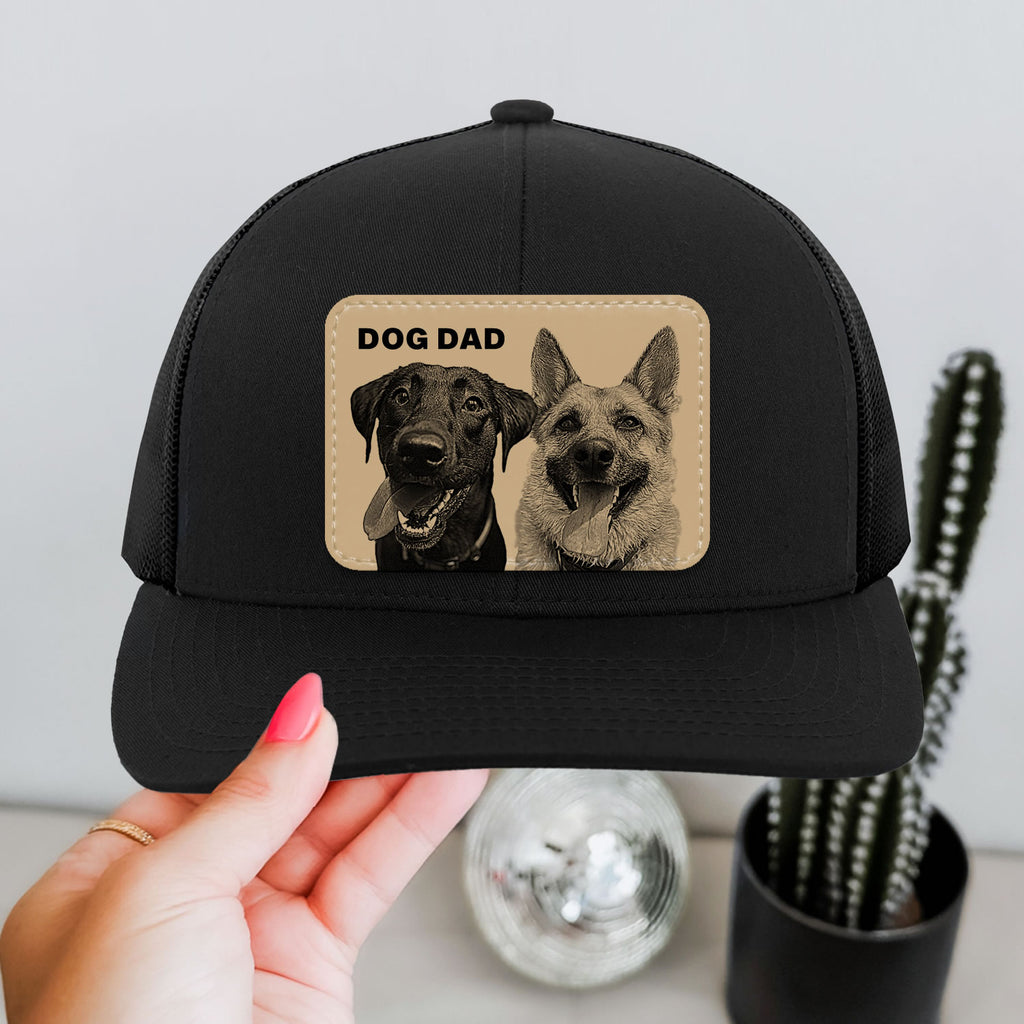 Black cap with 'Dog Dad' text and dog images held by a hand.