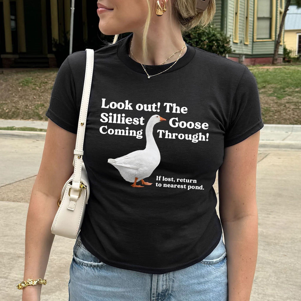 Person wearing a black t-shirt with a goose graphic and text, standing outdoors.
