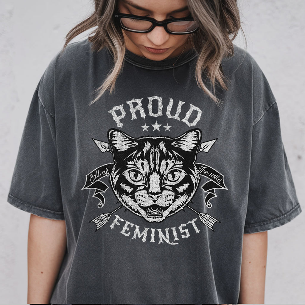 Person wearing a black t-shirt with a cat graphic and text 'Proud Feminist' on a plain background