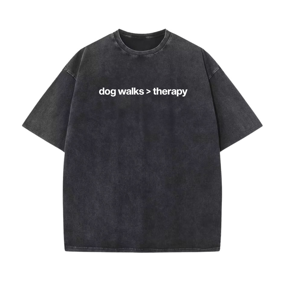 Washed black oversized cotton t‑shirt with drop shoulder design and white text “dog walks > therapy” — unisex funny dog lover graphic tee.